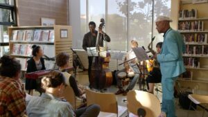 A group of five musicians performs for an audience in a library