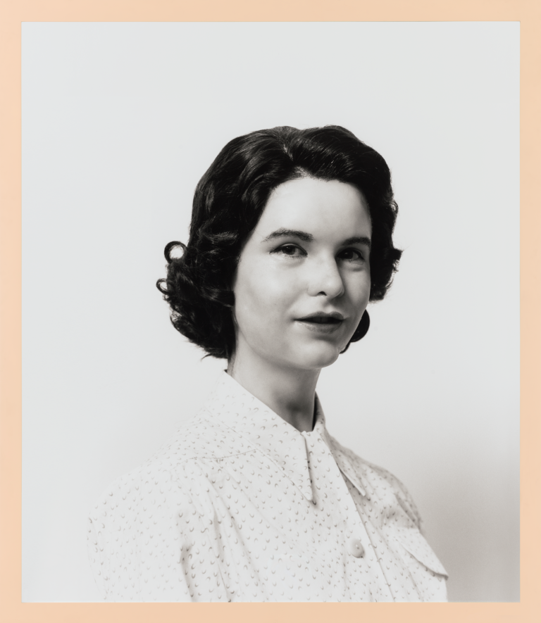 An uncanny black and white photograph of a white woman with 1950's style hair and blouse