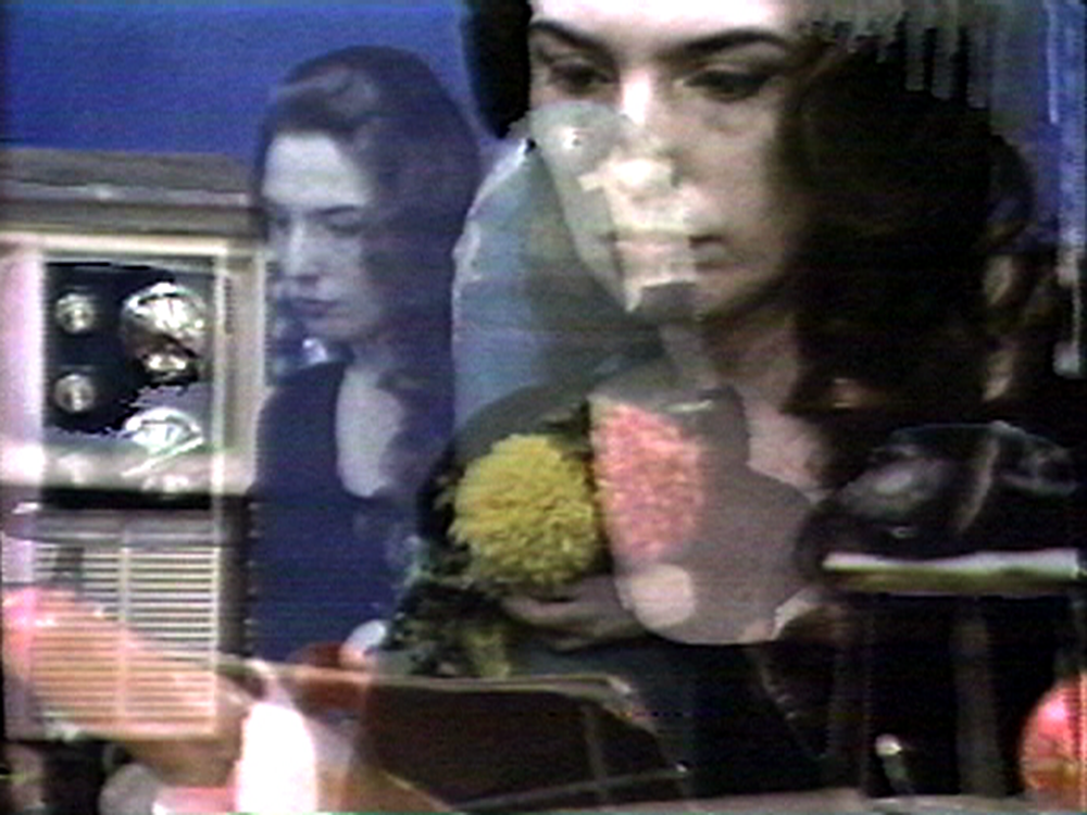 Still of a video collage containing multiple bviews of the same woman, a television and a black telephone