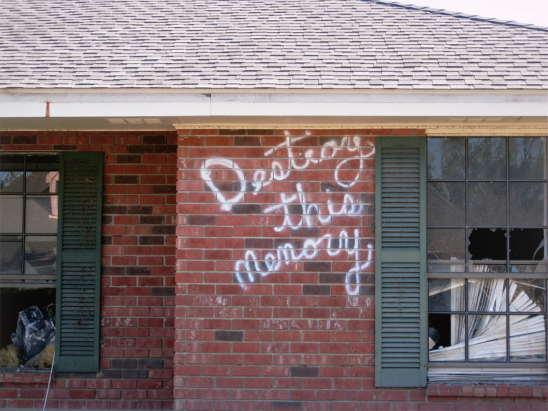 A house with the words " Destroy this memory" spray-painted on the side
