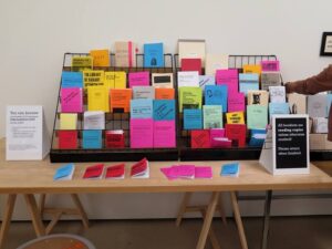 A color photograph of a wrack containing brightly colored pamphlets, Public Knowledge