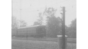 A black-and-white film still of an approaching train