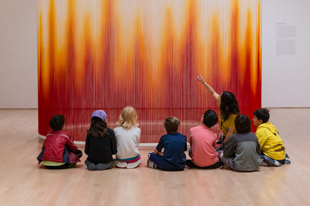 children on a school visit observing a yellow and red circular work of art