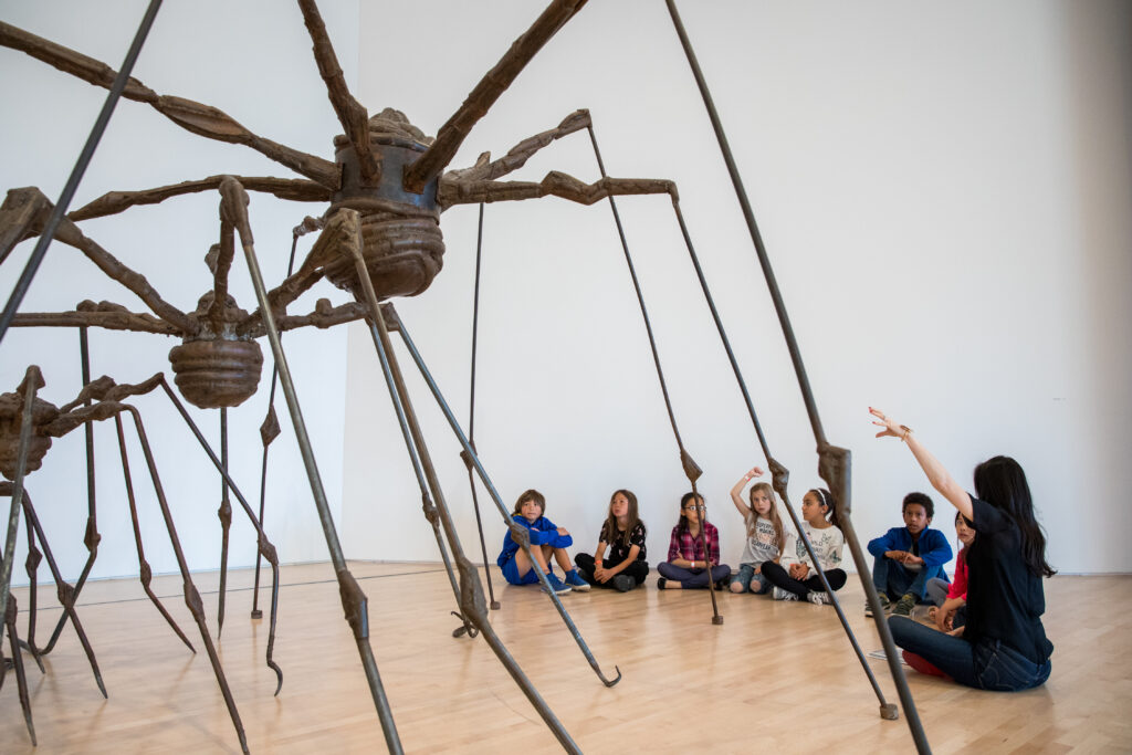 Children in gallery looking at three spider sculptures