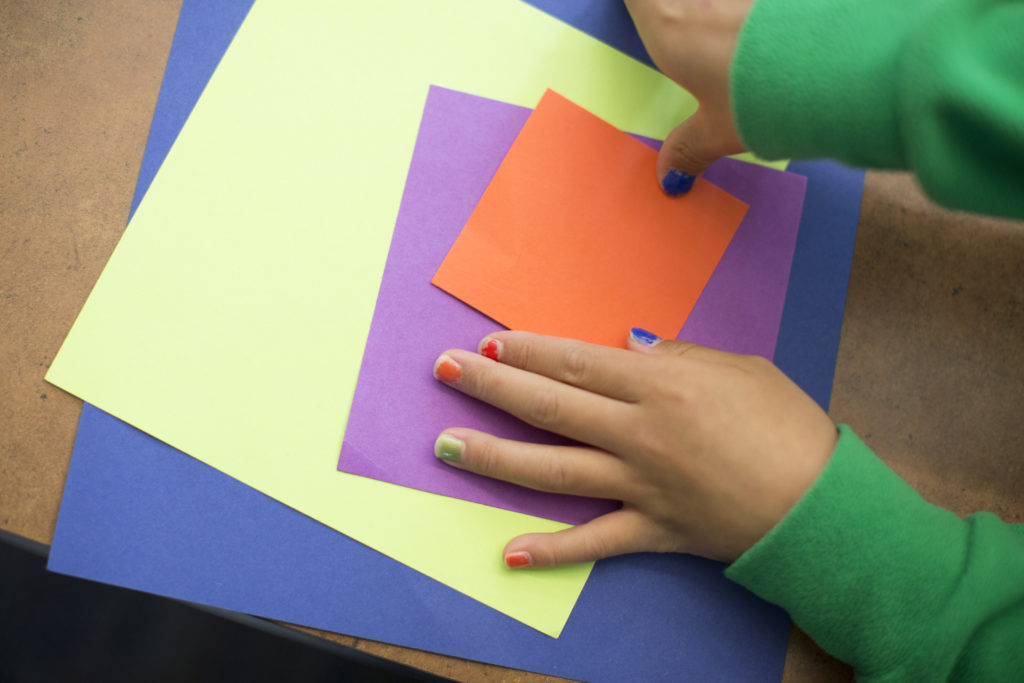 Child organizing color sheets of construction paper