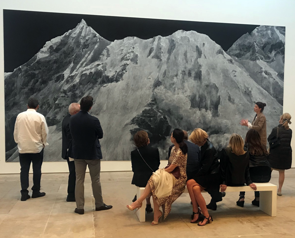 group of people looking at a mountain landscape painting