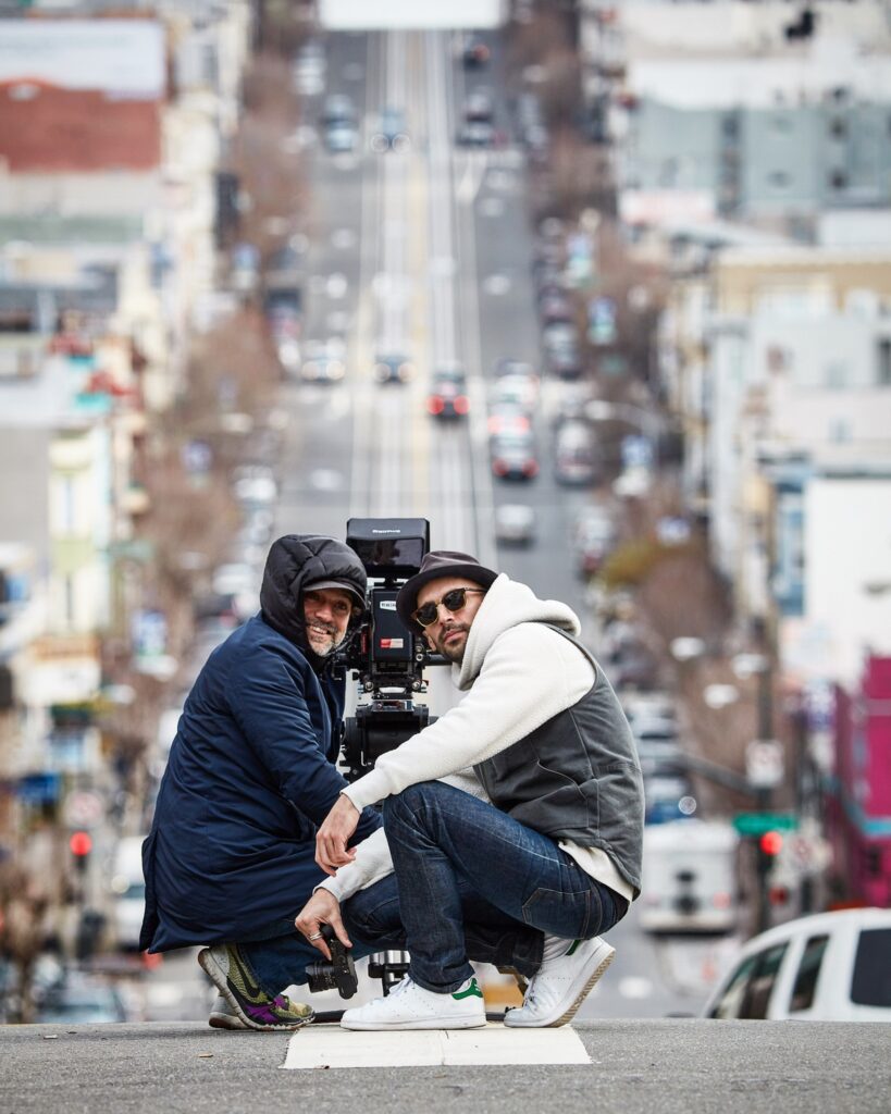 two people posing for a photograph on a sloped city street