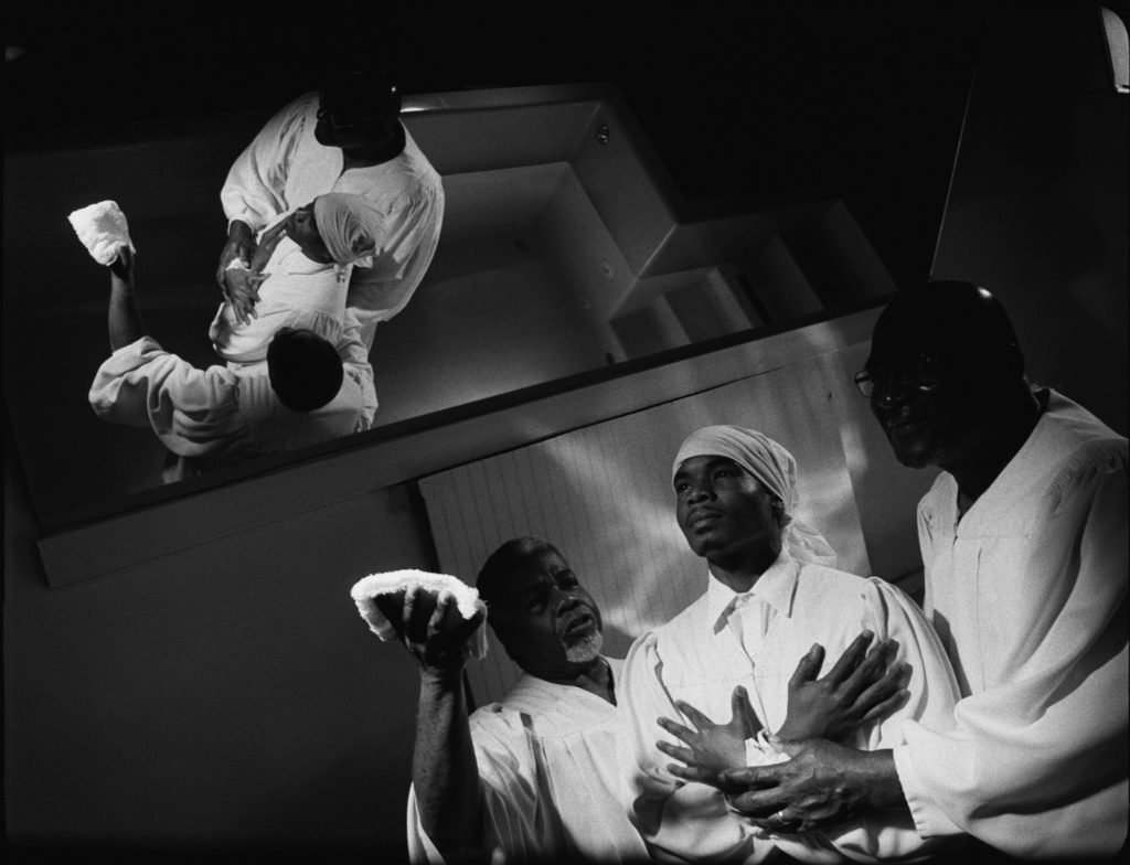 Black and white film still of three men in white religious garments.