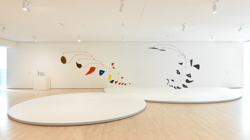 An installation view of two of Alexander Calder's kinetic sculptures as they hang in the museum gallery.