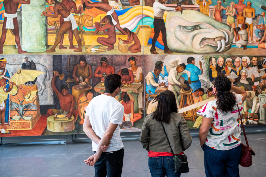 Three visitors view Diego Rivera's Pan American Unity mural.