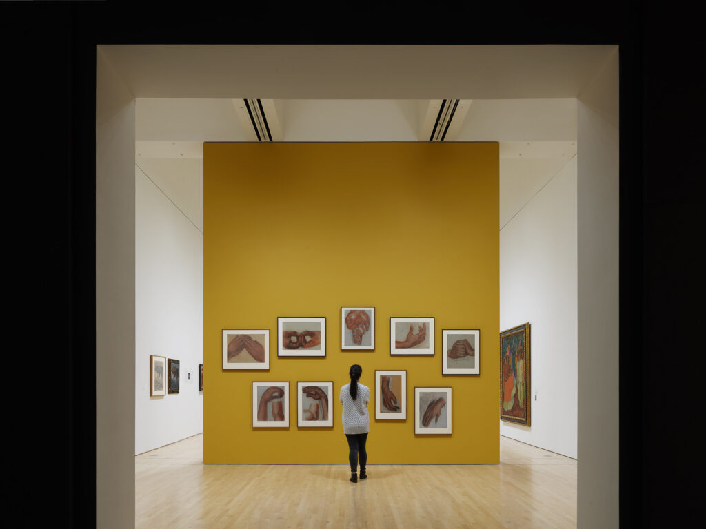 A museum visitor looks at a wall of artworks by Diego Rivera in the exhibition "Diego Rivera's America."