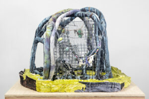 The artwork Hard Swamp Ecstatic Return by artist Anna Sew Hoy shows hand-built clay arches over a metal cage and denim scraps.
